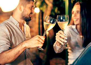 Ein Mann und eine Frau stoßen mit Weißwein an